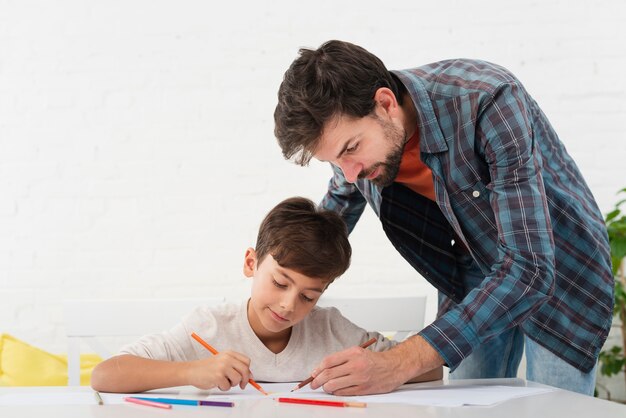 Padre mirando a su hijo haciendo la tarea