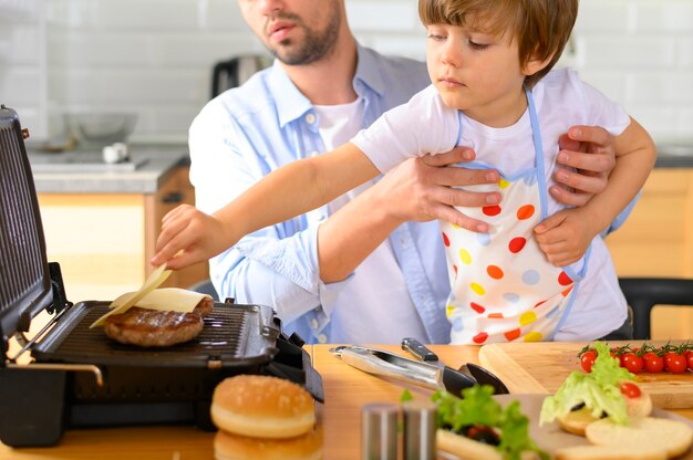 Padre monoparental y niño haciendo deliciosas hamburguesas