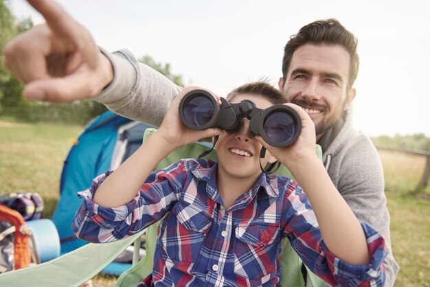 Padre mostrando a su hijo el mundo a través de binoculares