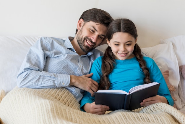 Padre y niña en la cama leyendo