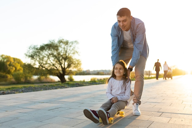 Padre y niña de tiro completo divirtiéndose con patineta