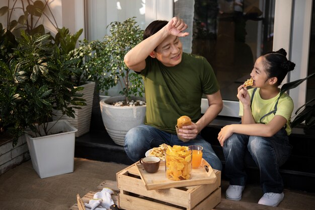 Padre y niña de tiro completo tomando un descanso para almorzar