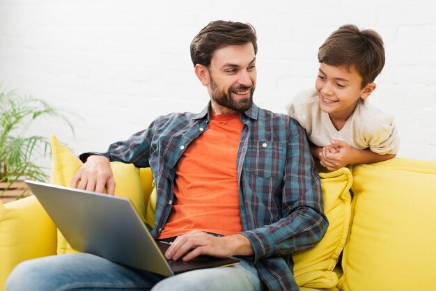 Padre y niño lindo mirando en la computadora portátil