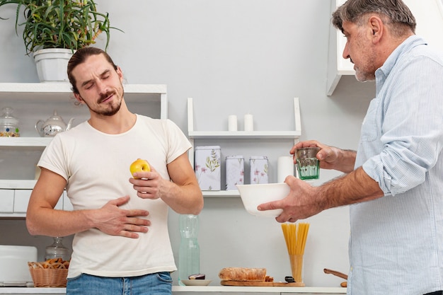 Foto gratuita padre ofreciendo a hijo un vaso de agua y un tazón