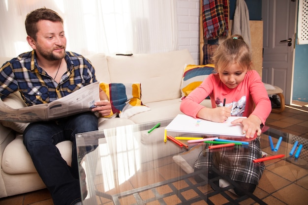 Padre orgulloso mirando a su hija dibujar