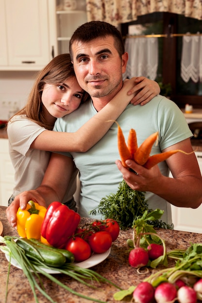 Padre posando con su hija en la cocina mientras prepara la comida