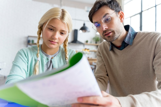 Padre siendo tutor de su hija y sosteniendo un libro