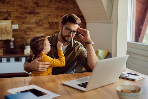 Foto gratuita padre soltero leyendo correo electrónico problemático en una computadora portátil mientras trabaja en casa