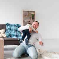 Foto gratuita padre sonriente con bebé en casa