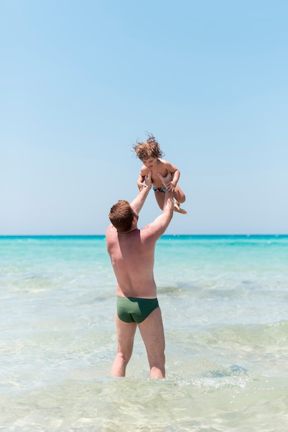Padre sosteniendo al niño en la playa
