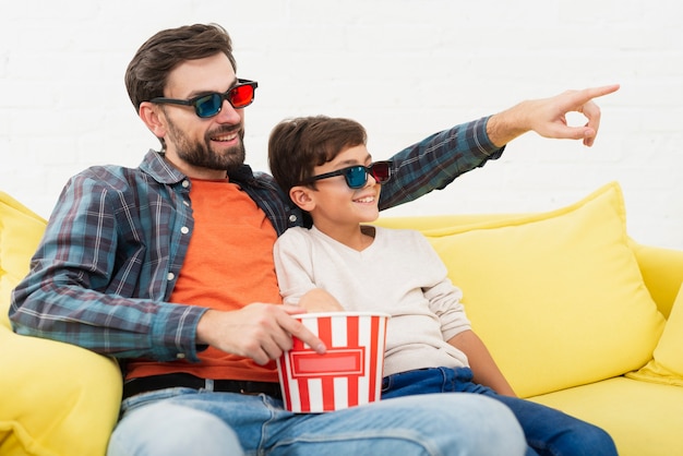 Padre sosteniendo palomitas de maíz y viendo una película con su hijo