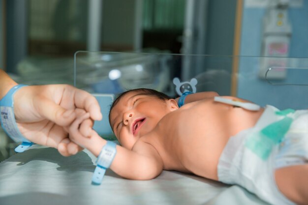 El padre sostiene la mano del bebé recién nacido en pañales