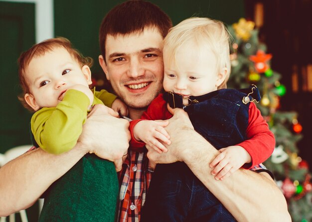 El padre sostiene en las manos a sus hijos