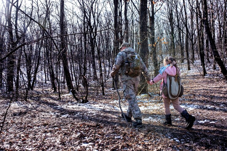 Foto gratuito padre y su hija caminando en el bosque de principios de invierno vestidos con ropa de trekking camunflage