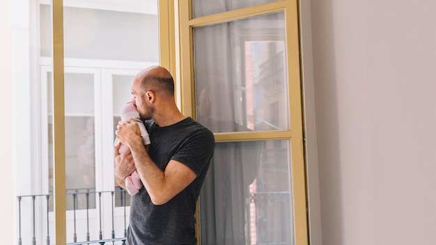 Padre sujetando bebé enfrente de ventana