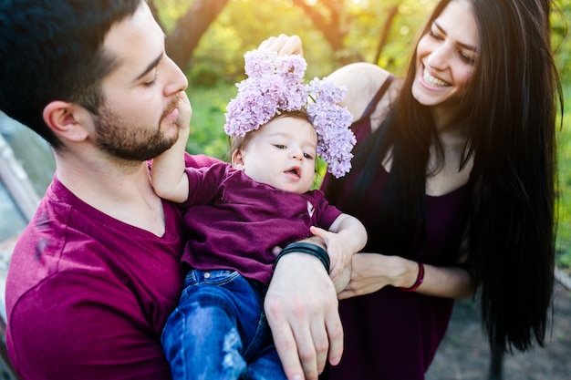 Foto gratuita padre sujetando un bebé mientras su madre le pone una corona de flores