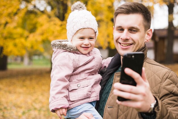 Padre, tenencia, hija, sonriente, y, hacer, selfie, juntos