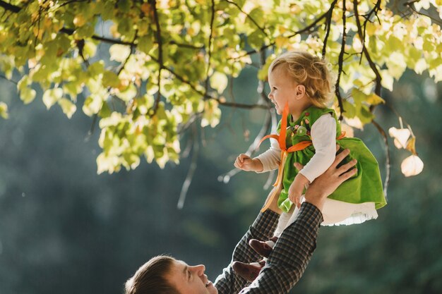 El padre tiene de manos a su hija en el parque