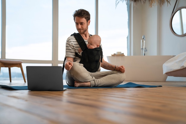 Foto gratuita padre de tiro completo sosteniendo al bebé mientras medita