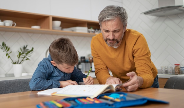 Padre de tiro medio ayudando al niño con la tarea