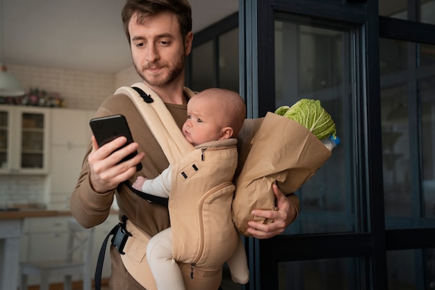 Padre de tiro medio con bebé y teléfono