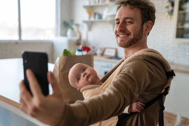 Foto gratuita padre de tiro medio con bebé y teléfono