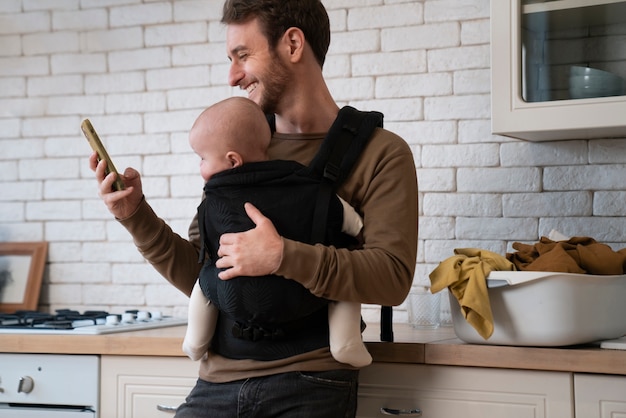 Foto gratuita padre de tiro medio con bebé y teléfono