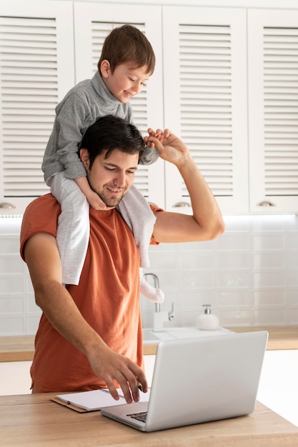 Foto gratuita padre de tiro medio sosteniendo niño y trabajando