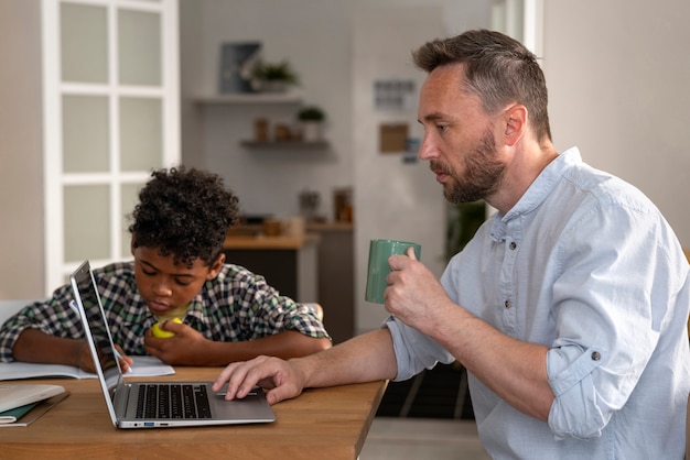 Foto gratuita padre de tiro medio trabajando en la computadora portátil