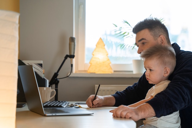 Padre de tiro medio trabajando con un niño en casa