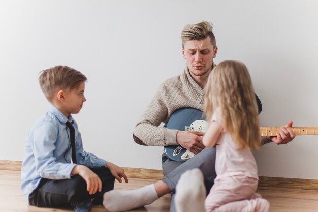 Padre tocando la guitarra junto a sus hijos