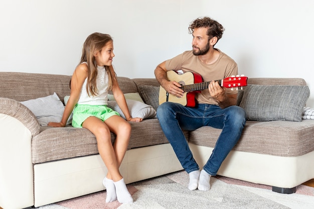 Foto gratuita padre tocando la guitarra para su hija