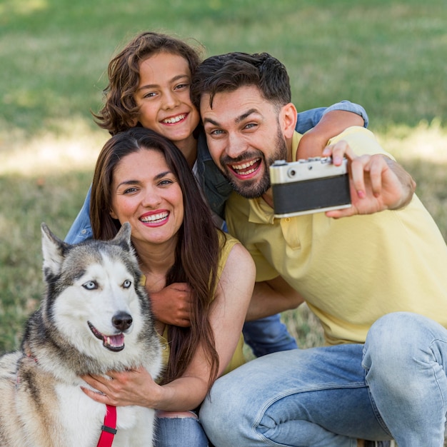 Padre tomando selfie de la familia y el perro mientras está en el parque