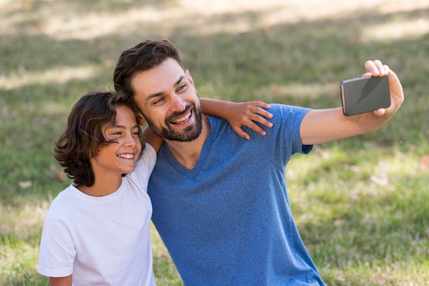 Foto gratuita padre tomando un selfie con su hijo mientras está al aire libre