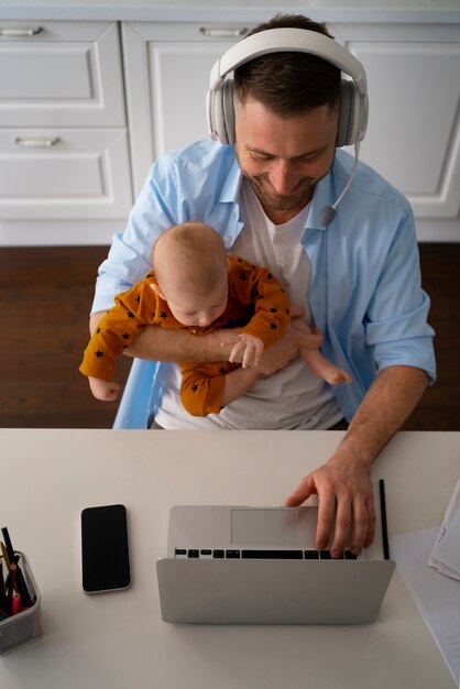 Padre trabajando desde casa tratando de equilibrar la vida familiar con el niño y el trabajo