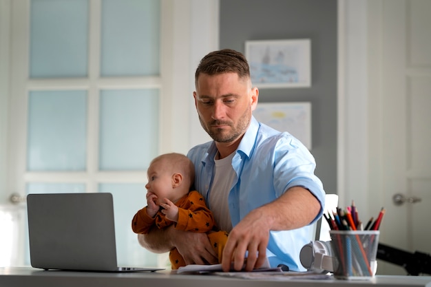 Padre trabajando desde casa tratando de equilibrar la vida familiar con el niño y el trabajo