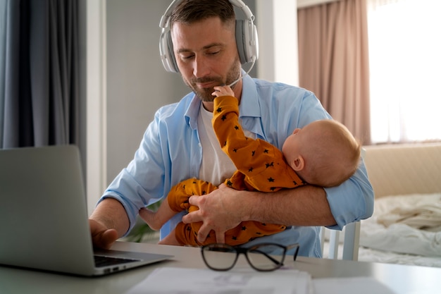 Padre trabajando desde casa tratando de equilibrar la vida familiar con el niño y el trabajo