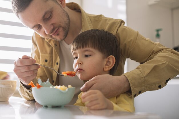 Padre tratando de alimentar a su hijo