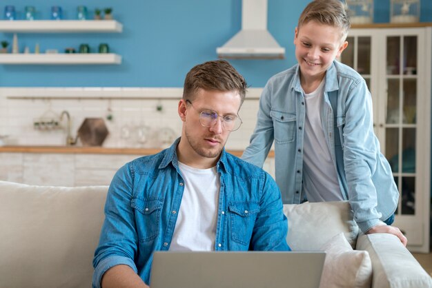 Padre usando la computadora portátil e hijo mirando