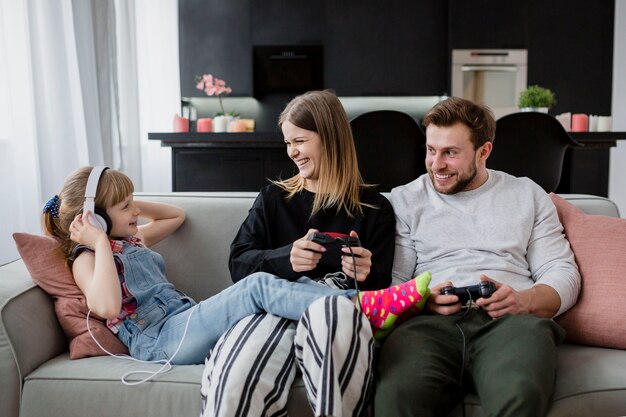 Padres alegres jugando videojuegos cerca de la hija