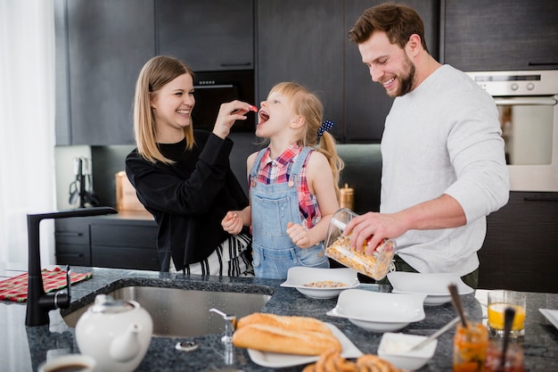 Padres alimentando a su hija en la cocina