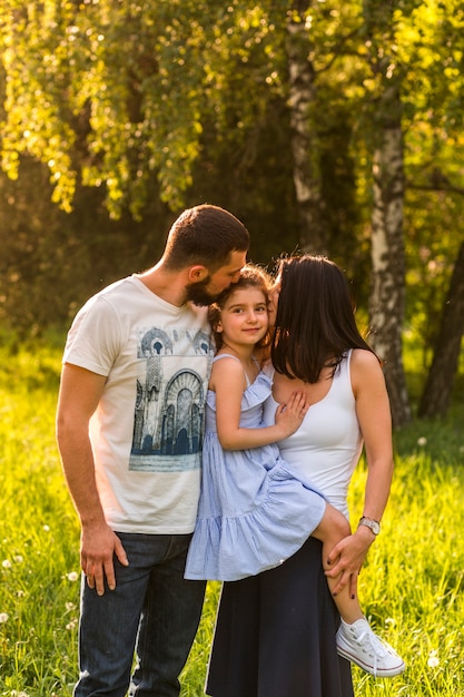 Foto gratuita padres amorosos besando a su hija en el parque