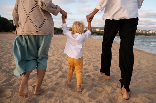 Foto gratuita padres con un bebé en la playa al atardecer