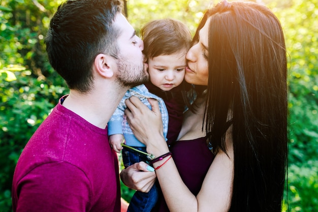 Foto gratuita padres besándo a su bebé