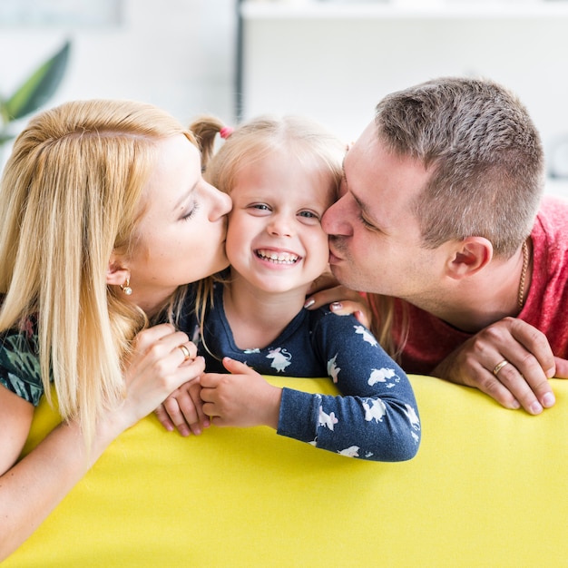 Los padres besando a su pequeña hija