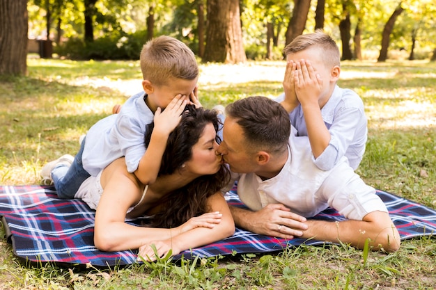 Padres besándose mientras los niños se tapan los ojos