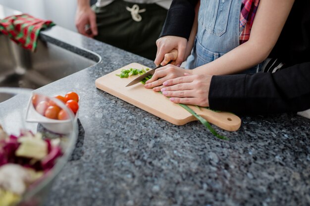 Los padres de los cultivos y la hija cortar verduras