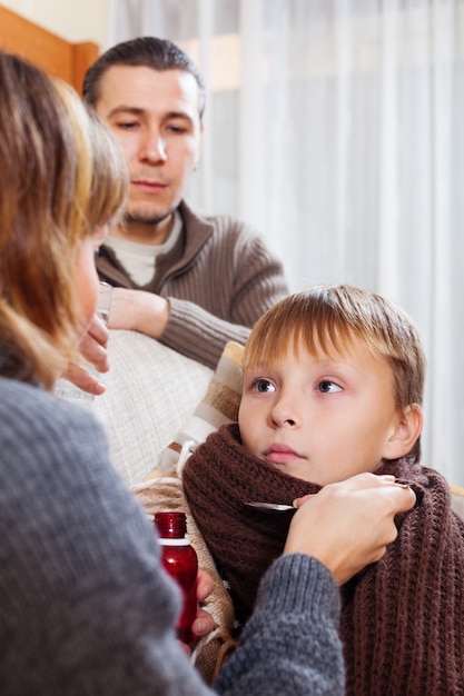 padres dando jarabe medicinal al adolescente