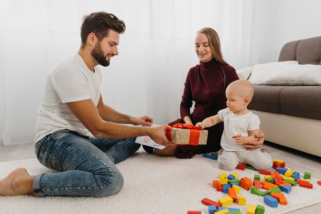 Padres dando regalo a su bebé en casa.