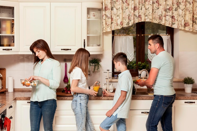 Padres e hijos preparando comida en la cocina para la cena.